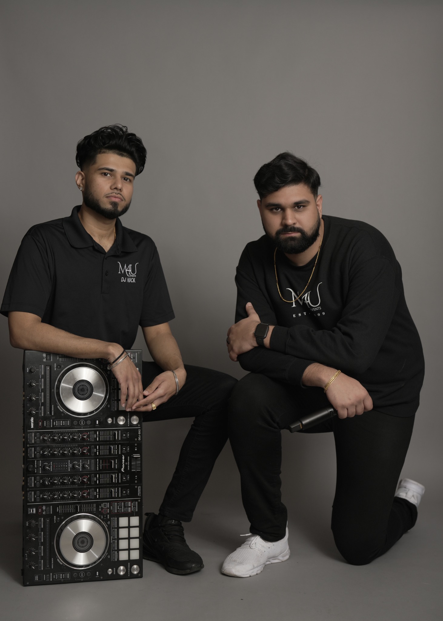 SharmaSync in M4U apparel with DJ decks and a microphone